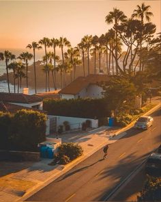 an aerial view of the ocean with palm trees and houses in the background at sunset