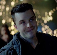 a young man smiling at the camera with lights in the background