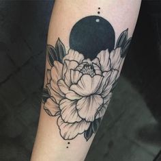 a black and white flower tattoo on the left arm, with an moon in the background