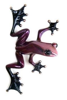 a purple and black frog sitting on top of a white wall