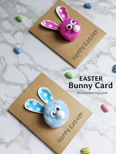 two easter bunny cards on a table with eggs and candies in the back ground