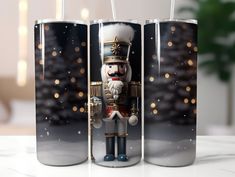 two tin canisters decorated with a nutcracker and christmas tree in the background