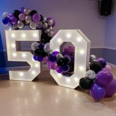 the number 50 is surrounded by balloons and streamers in purple, black, and silver colors