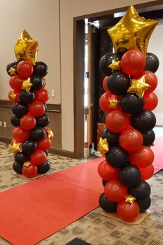 two tall black and red balloons with gold stars on them in the middle of a room