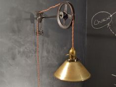 an old fashioned wall lamp hanging from the side of a gray wall with writing on it