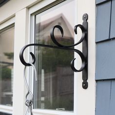 a black metal hook on the side of a house with a window in the background