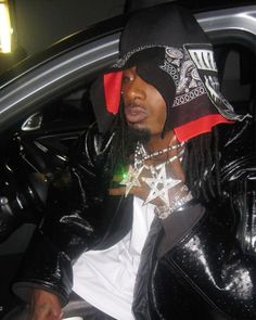 a man sitting in the back seat of a car wearing a black hat and jacket