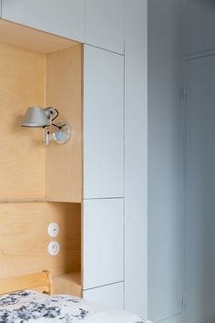 a bed with a wooden headboard and two lights on the wall next to it