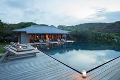 an outdoor pool with chaise lounges next to it and the water in front