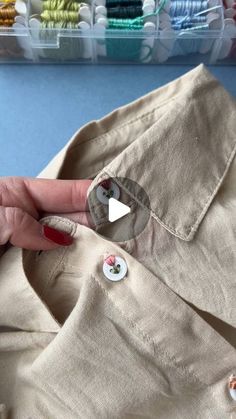 a woman's hand holding onto buttons on a shirt