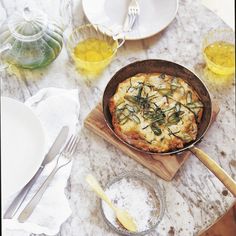 a pan with some food in it sitting on a table next to plates and utensils