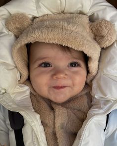 a baby wearing a bear hat in a stroller jacket with hood over it's face