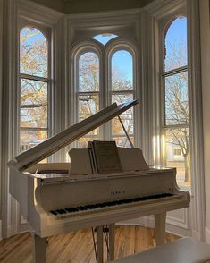 a grand piano sitting in front of two windows