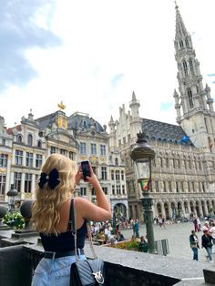 a woman taking a photo in front of an old building