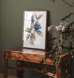 there is a vase with flowers on the table next to it and a framed photo