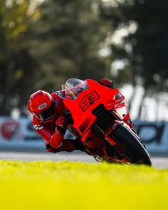 a person riding a motorcycle on a race track with grass and trees in the background