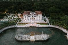 an aerial view of a large white building next to a body of water with trees in the background