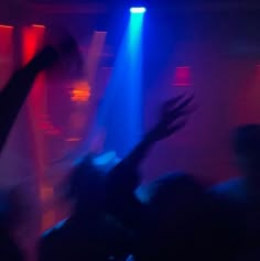 people dancing at a party with their arms in the air and lights on behind them