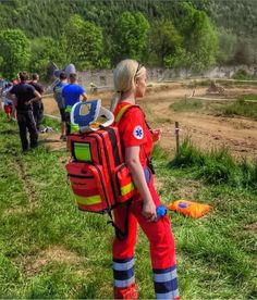 a woman in an orange fireman's uniform is standing on the grass with her back to the camera