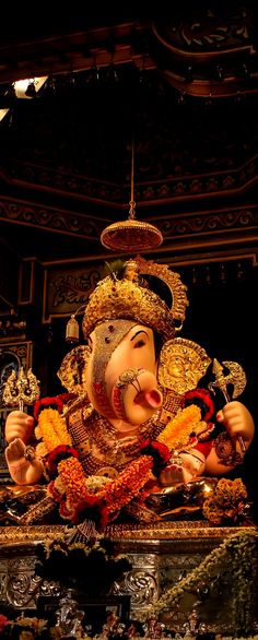 a statue of ganesh in the middle of a room filled with flowers and other decorations