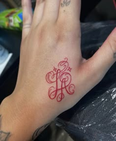 a person's hand with a red tattoo on it and the letter h written in cursive writing