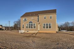 a large brown house sitting in the middle of a dirt field next to a road