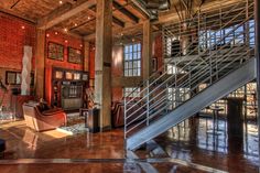 the inside of a building with red brick walls and metal staircase leading up to an open floor plan