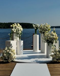 an outdoor ceremony setup with white flowers and greenery in vases on the ground