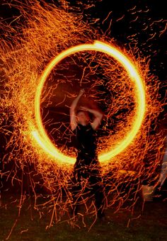 a person holding a fire ring in the air with their arms and legs spread out