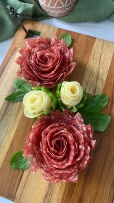 some flowers are sitting on a cutting board with green leaves and meat in the middle