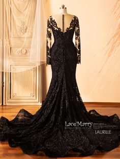 the back of a black lace wedding dress on display in front of a white wall