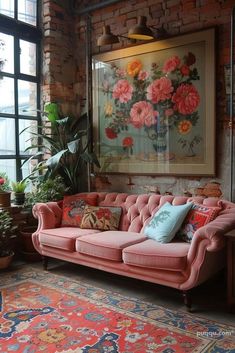 a pink couch sitting in front of a window next to a rug and potted plants