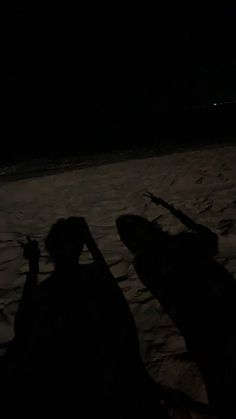 two people sitting in the snow at night with their skis propped up against them