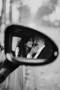 a man and woman are kissing in the side view mirror