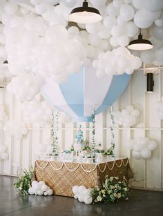 a table topped with white balloons next to a cake