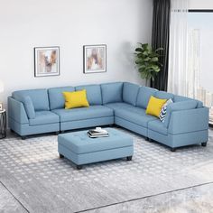 a living room with a blue sectional couch and yellow pillows on the end table in front of a large window