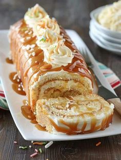 a cake roll with caramel drizzle and whipped cream on top sitting on a white plate