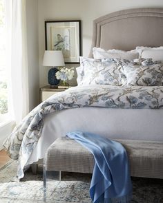 a bed with blue and white comforter in a bedroom next to a window on an area rug