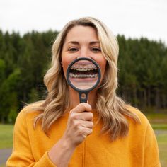 a woman holding a magnifying glass looking at the camera with a smile on her face