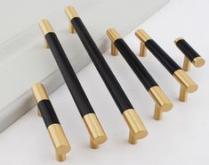 four black and gold handles on a white surface