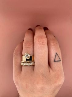 a woman's hand with two different rings on her fingers and one has a triangle tattoo