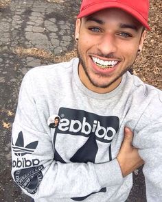 a man in a red hat is posing for the camera with his arms crossed and smiling