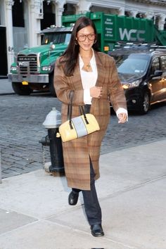 a woman walking down the street carrying a purse