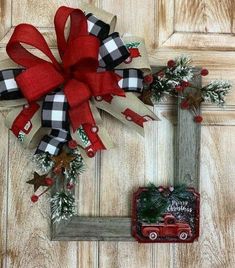 a red and black christmas wreath on a wooden door with an old truck ornament