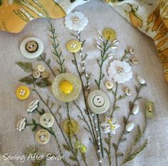 a bunch of buttons and flowers sitting on top of a pillow