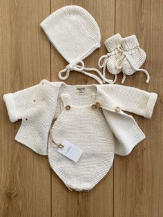 three pieces of knitted clothing are laid out on a wooden floor with tags attached to them