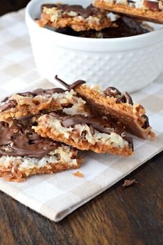 chocolate covered cookies are on a napkin next to a bowl full of nuts and marshmallows