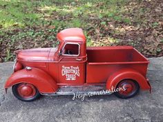 an old red truck is parked on the side of the road in front of some grass