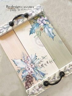 a wooden board with flowers and leaves painted on the side, attached to an iron hook