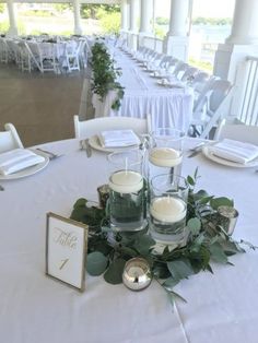 the centerpieces on this table are filled with candles and greenery